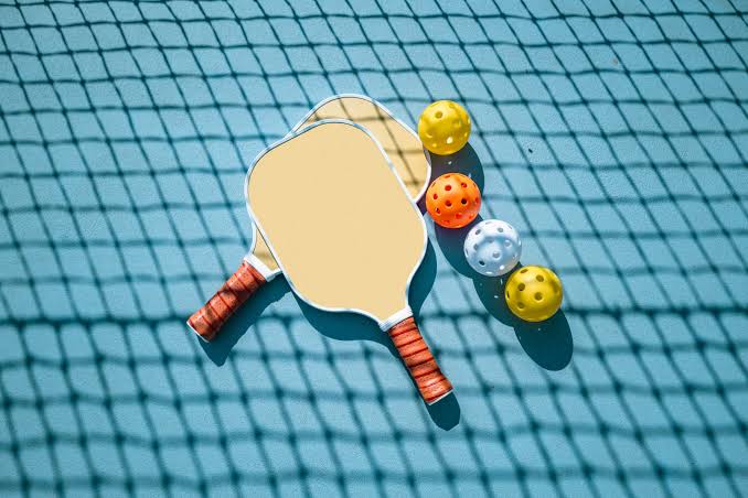 Pickleball paddle and ball demonstrating carbon fiber composite construction